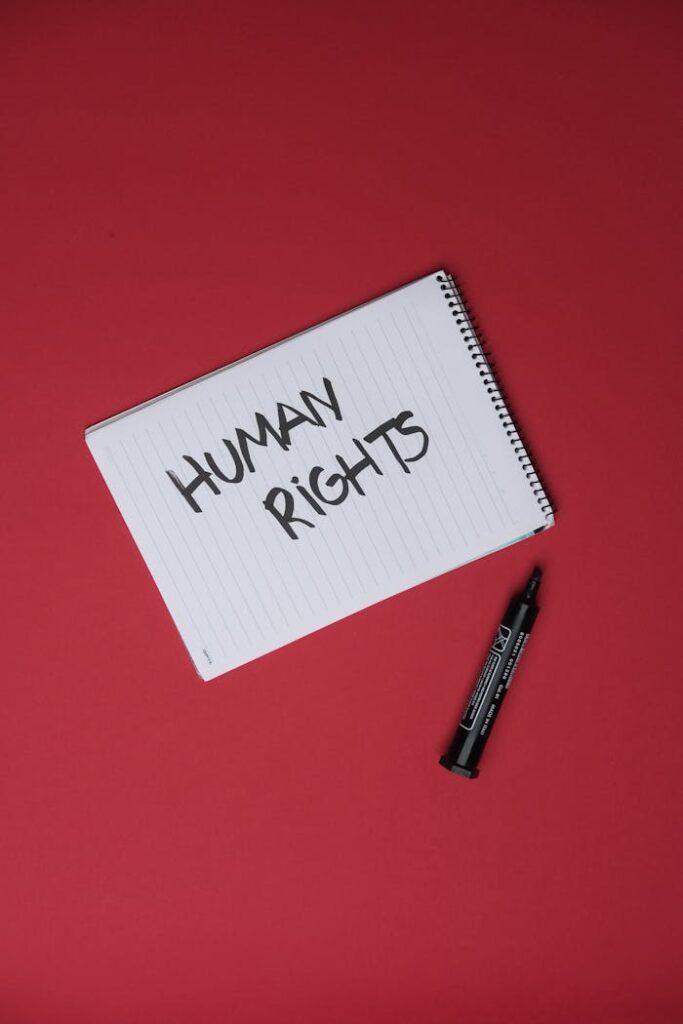 Notepad on red background with 'Human Rights' written, highlighting social justice.